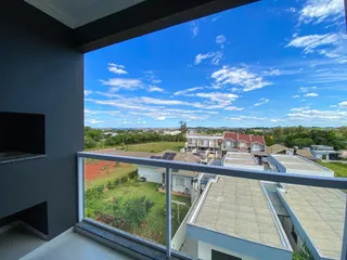Vista panorâmica de casas e área verde sob um céu azul com nuvens.