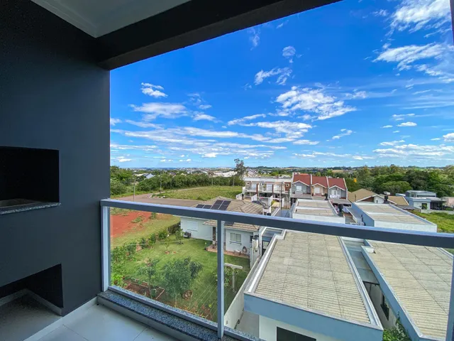 Vista panorâmica de casas e área verde sob um céu azul com nuvens.