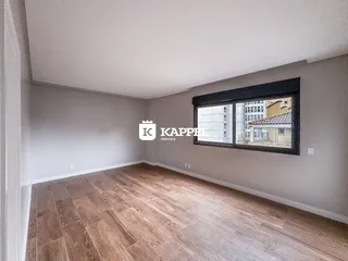 Foto de um cômodo interno com piso de madeira clara e uma janela grande.