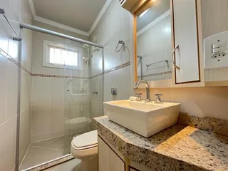 Banheiro com box de vidro e bancada de mármore.