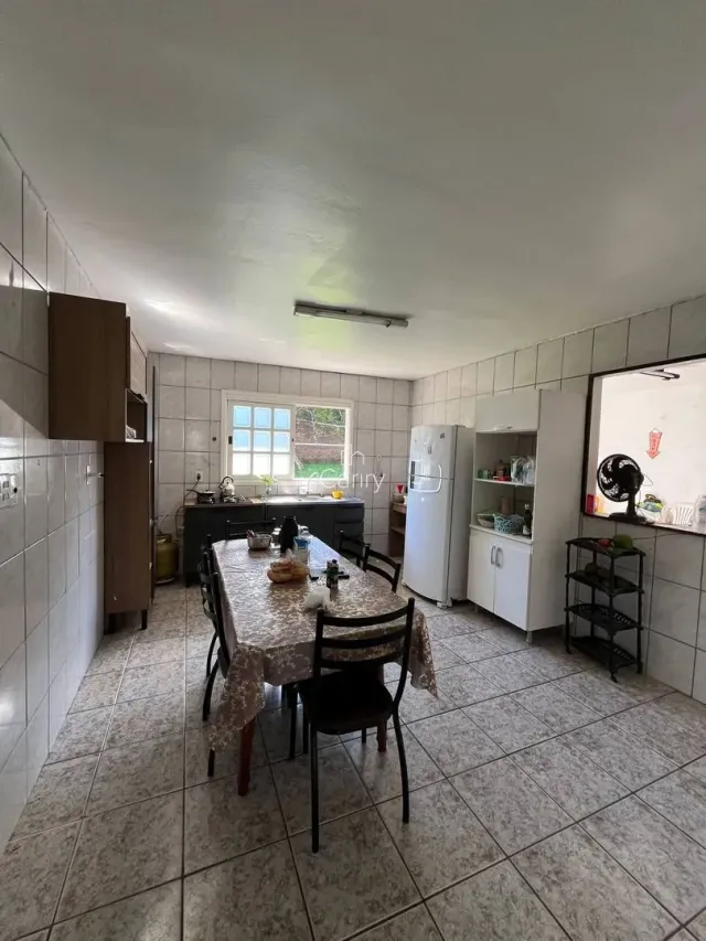 Uma sala de jantar com mesa e cadeiras de madeira e piso de cerâmica.