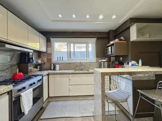 Foto de uma cozinha moderna com armários brancos e bancadas de granito.