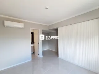 Hall de entrada com paredes brancas e piso claro.