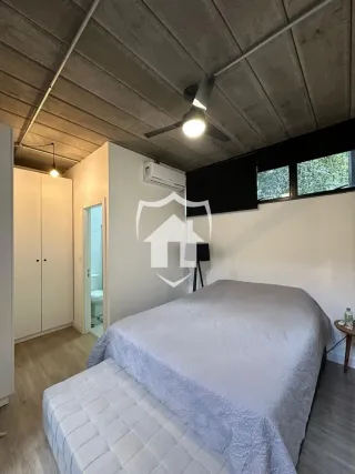 Quarto com cama e teto de concreto aparente em imóvel no Brasil.