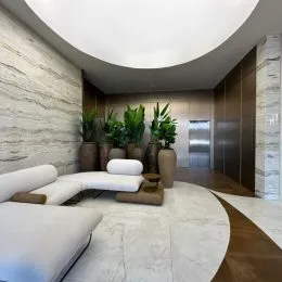 Hall de entrada com paredes revestidas em pedra clara e teto curvo.