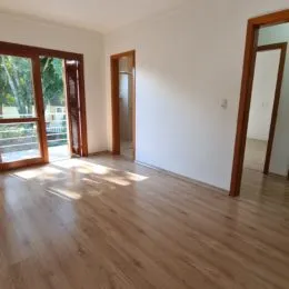 Vista interna de um ambiente com piso de madeira e porta de acesso.