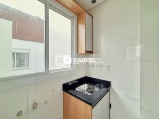 Uma bancada de cozinha com armários de madeira e superfície escura é visível na imagem.
