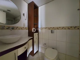 Foto de um banheiro com azulejos e armário de madeira.
