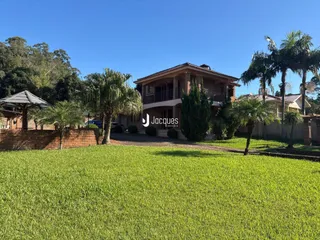 Fachada de uma casa com jardim e palmeiras em Lajeado, Brasil.