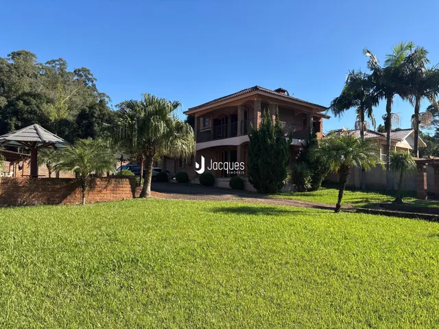 Fachada de uma casa com jardim e palmeiras em Lajeado, Brasil.