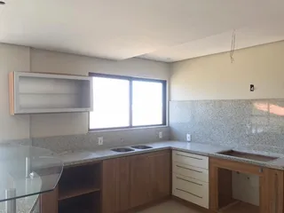 Vista da cozinha com armários de madeira e bancadas claras.