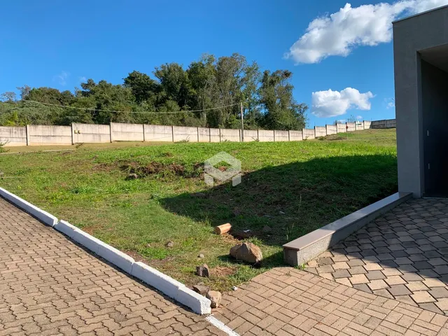 Vista externa de um terreno gramado com cerca e calçada de tijolos.
