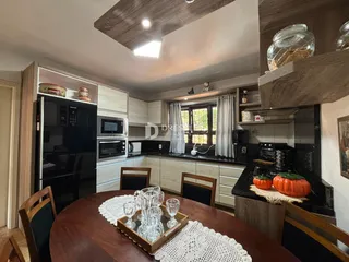Ambiente de cozinha e jantar com armários e mesa de madeira.