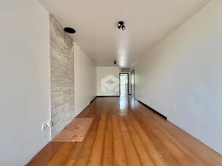 Corredor interno com piso de madeira e paredes brancas.