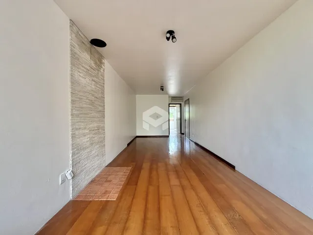 Corredor interno com piso de madeira e paredes brancas.
