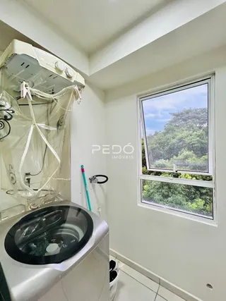 Foto de um interior mostrando uma máquina de lavar e uma janela com vista para a vegetação.