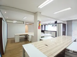 Ambiente interno de um espaço amplo com piso de madeira clara e móveis modernos.