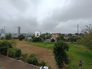 Vista aérea de um terreno com vegetação e paisagem urbana ao fundo.