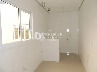 Vista interna de um ambiente com paredes brancas e janelas.