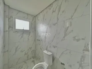 Foto de um banheiro com revestimento de mármore claro.