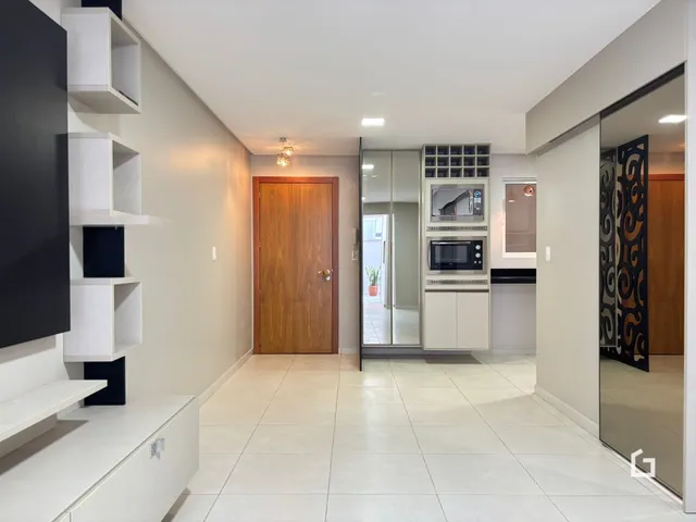 Ambiente interno de um apartamento com piso de cerâmica e estantes brancas.