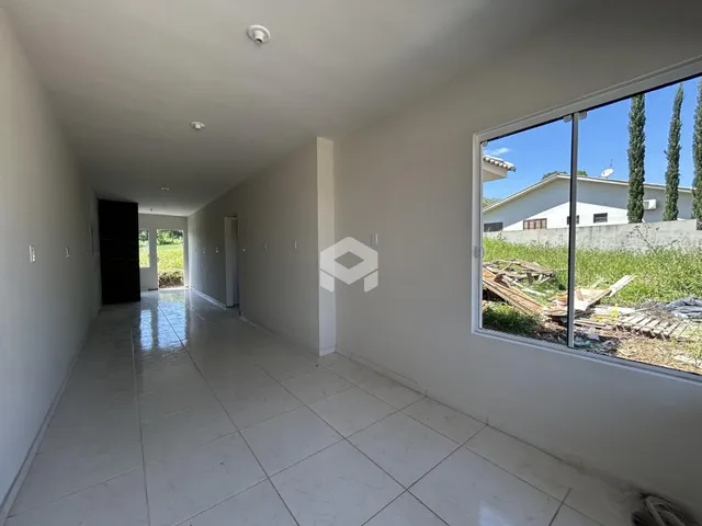 Corredor interno de uma residência com piso de cerâmica branca.