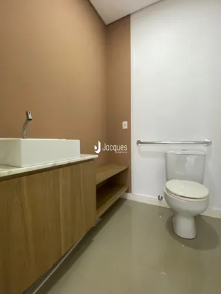 Foto de um banheiro interno com bancada de madeira e louças sanitárias brancas.
