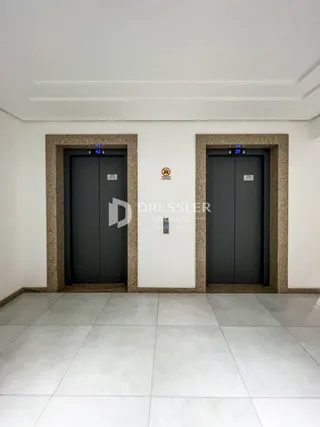 Hall de entrada com portas escuras e paredes brancas.