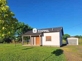 Fachada de uma casa simples com telhado escuro em um ambiente gramado.