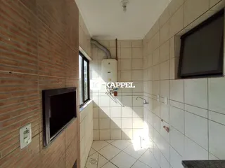 Foto de um corredor interno com paredes de tijolo aparente e piso cerâmico.