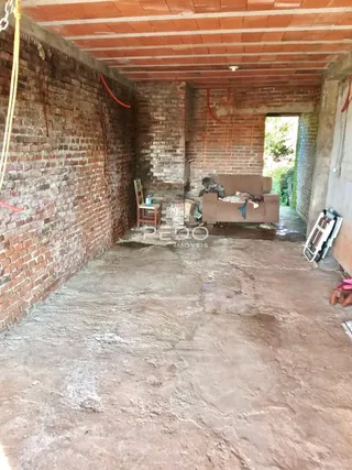 Espaço interno com paredes de tijolo aparente e piso de concreto.