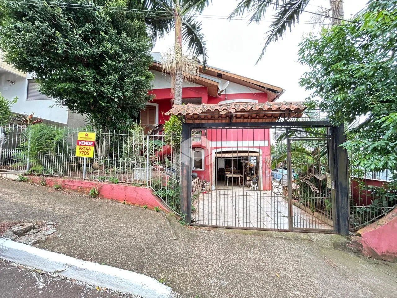 Fachada de uma residência em Lajeado, Brasil, com portão de ferro e cerca.