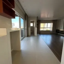 Hall de entrada com piso claro e grandes janelas.