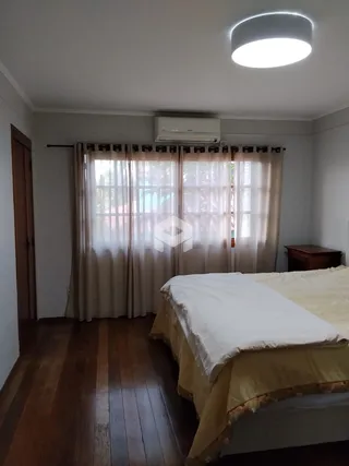 Foto de um quarto com cama e janela coberta por cortinas claras.