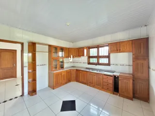 Foto interna de uma cozinha com armários de madeira e piso branco.