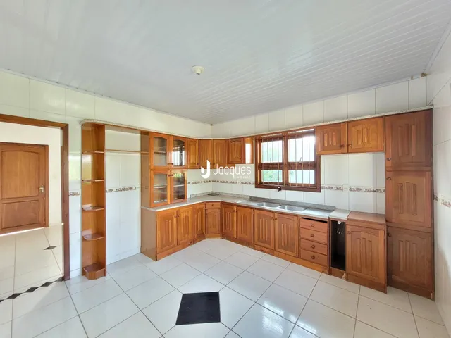 Foto interna de uma cozinha com armários de madeira e piso branco.