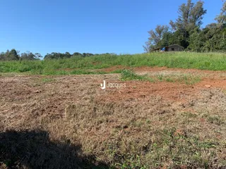 Campo de vegetação seca com uma residência ao fundo.