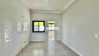 Hall de entrada com parede de azulejos brancos e uma janela.