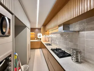 Cozinha moderna com armários de madeira e bancadas claras.