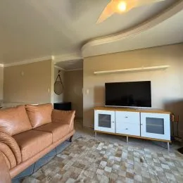 Foto de uma sala de estar com sofá e televisão montada na parede.