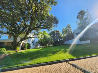 Vista externa de uma propriedade com gramado verde e um edifício branco ao fundo.
