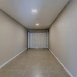 Foto de um corredor interno com paredes brancas e uma porta no final.