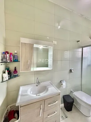 Banheiro com revestimento de cerâmica e bancada branca.