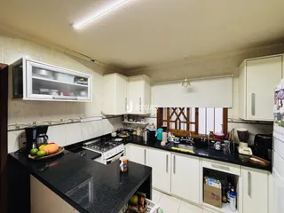 Foto da cozinha com armários brancos e bancadas escuras.
