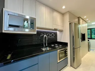 Cozinha moderna com armários brancos e bancadas pretas.