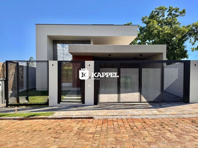 Fachada moderna de uma residência em Lajeado, Brasil, com portão de metal e paisagismo.
