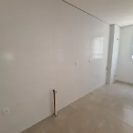 Vista interna de um ambiente com paredes brancas e piso claro.