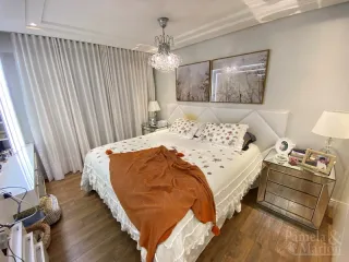 Quarto com cama grande e cortinas brancas.