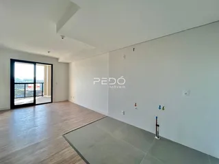 Sala ampla com piso de madeira e porta de vidro que dá para a vista.