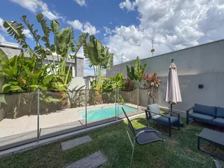 Vista do quintal com piscina e vegetação tropical.